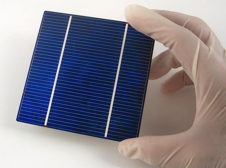 A researcher with protective gloves holds a solar panel module 