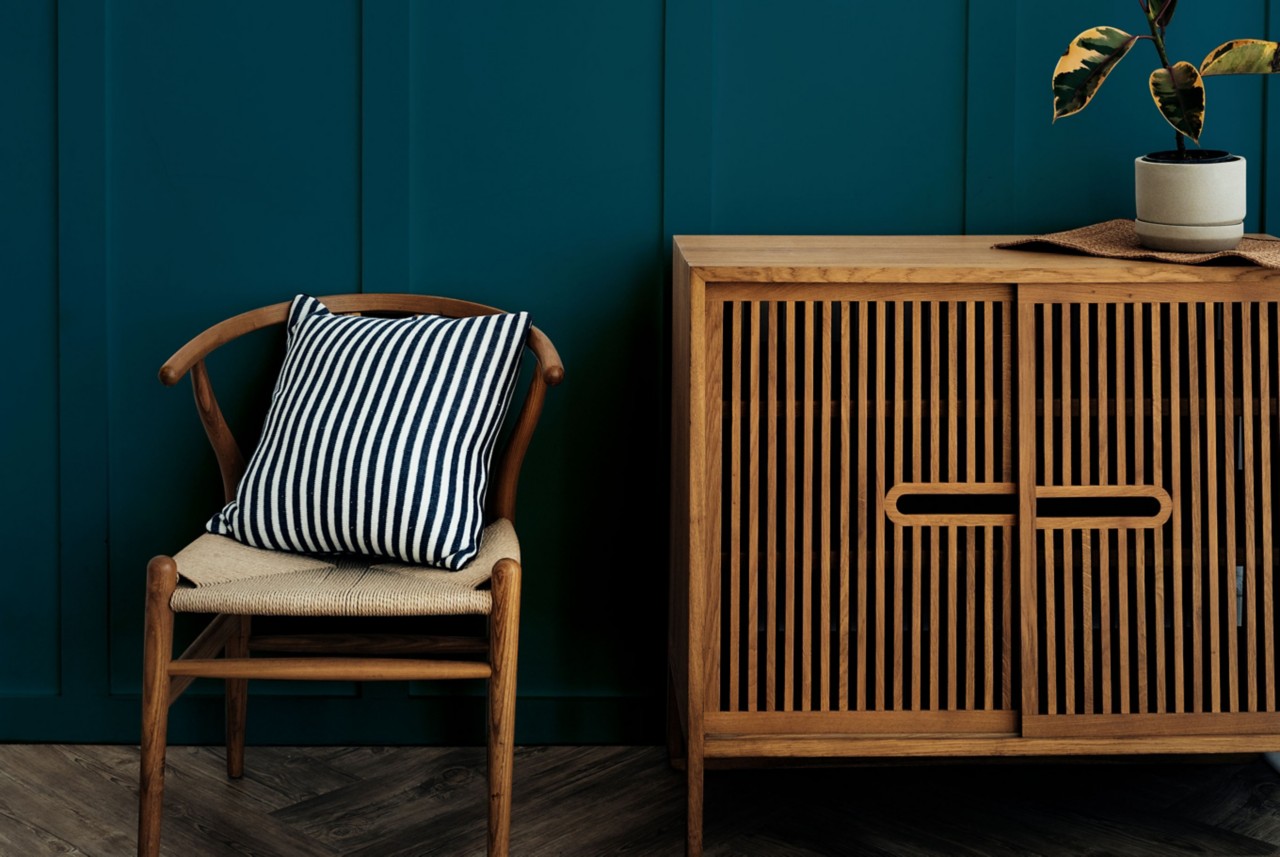 A wood chair and cabinet are placed along a wall. 