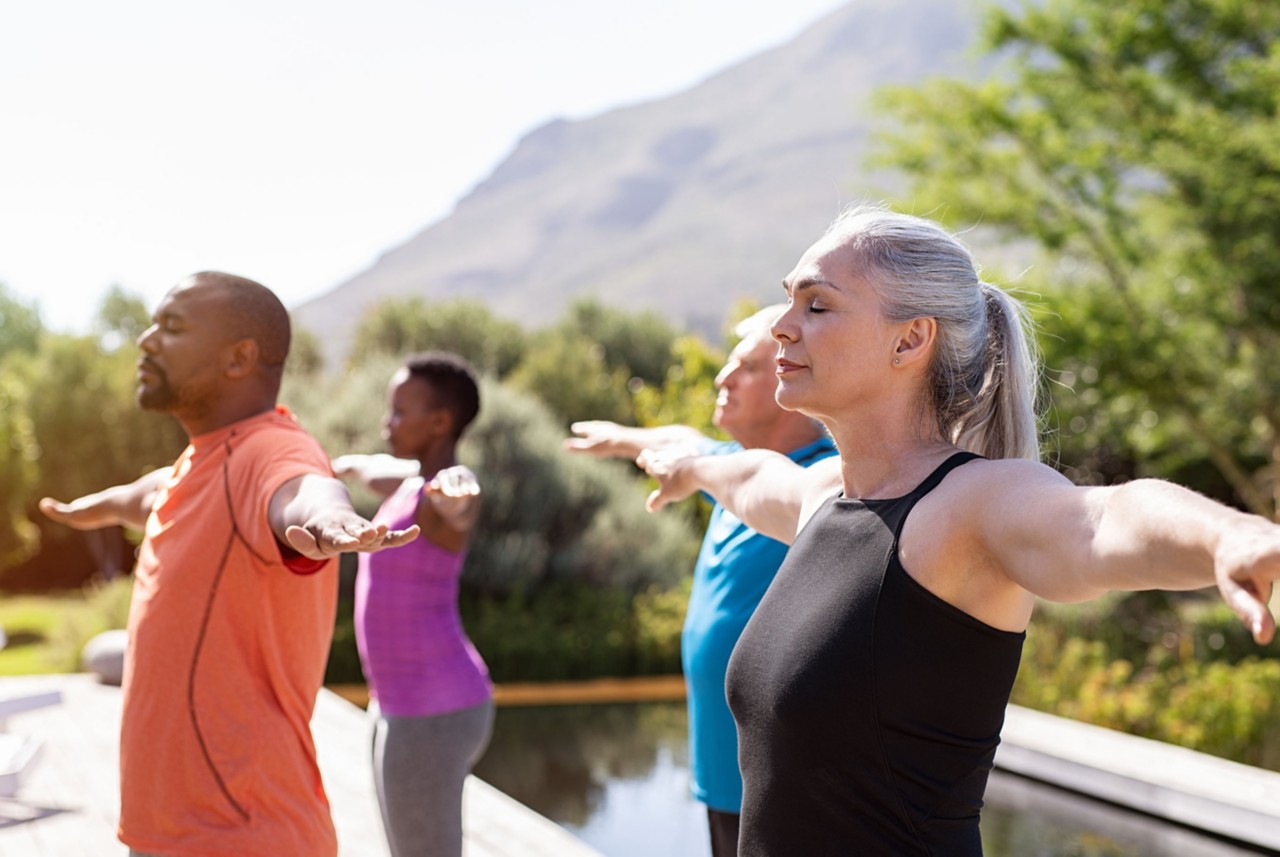 A group of people practicing outdoor yoga in the sun. 