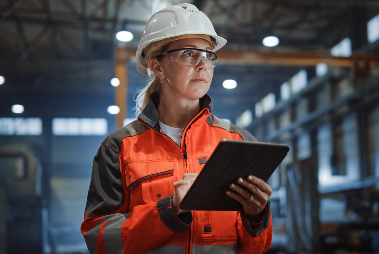 Coordinadora de seguridad usando equipos de protección personal y sosteniendo una tableta 